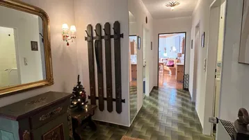 Langer Flur mit grünen Fliesen, einem antiken Schrank und einem großen Spiegel.