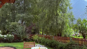 Gemütliche Terrasse mit Gartenmöbeln, umgeben von üppigem Grün und mit Blick auf die Berge.