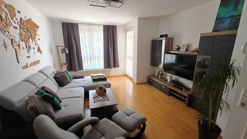 Helles Wohnzimmer mit modernem Sofa, Holzboden und Zugang zum Balkon.