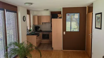 Offener Wohnbereich mit Holzboden und angrenzender Küche, hell und funktional.