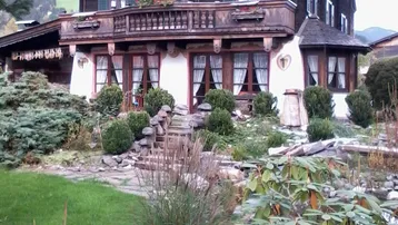 Traditionelles Holzchalet mit mehreren Balkonen und einem gepflegten Gartenbereich.