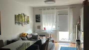 Heller Wohn- und Essbereich mit Holzboden, bequemer Couch und Zugang zum Balkon.