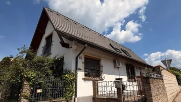 Charmantes Einfamilienhaus mit Satteldach, gepflegtem Vorgarten und schmiedeeisernem Zaun.