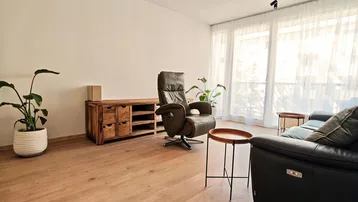 Geräumiges Wohnzimmer mit bequemen Sitzmöbeln, Holzboden und großen Fenstern für viel Tageslicht.