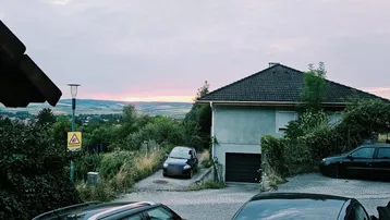 Hausfassade mit Garageneinfahrt und weitem Blick über die Landschaft bei Sonnenuntergang.
