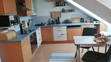 Funktionale Einbauküche mit Essbereich, Dachschräge und Laminatboden.