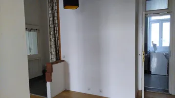 Heller Flur mit Holzparkettboden, der zu verschiedenen Räumen führt, inklusive Badezimmer.