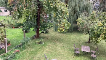 Großer Garten mit Rasenfläche, Obstbäumen und Sitzgelegenheiten für entspannte Stunden im Freien.