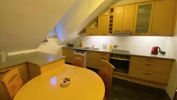 Gemütliche Küche im Dachgeschoss mit Holzeinbauten, Essbereich und schrägen Decken.
