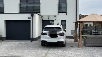 Modernes Reihenhaus mit Garage, Einfahrt und Balkonen unter bewölktem Himmel.
