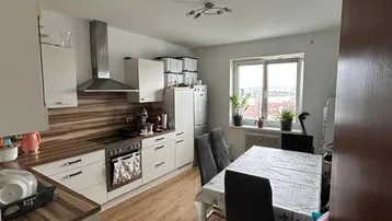 Helle Küche mit integriertem Essbereich, modernen weißen Schränken und Fensterblick auf die Stadt.