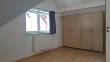 Helles Schlafzimmer im Dachgeschoss mit Einbauschränken und Holzfußboden.