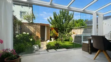 Heller Wintergarten mit Glasdach und Blick auf den gepflegten Garten, ideal zum Entspannen.
