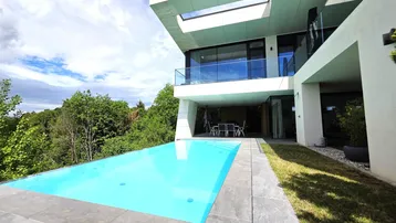 Der moderne Poolbereich der Villa bietet eine erfrischende Oase mit Blick ins Grüne.