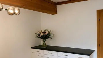 Gemütlicher Essbereich mit Holztisch, modernen Stühlen und sichtbaren Deckenbalken.
