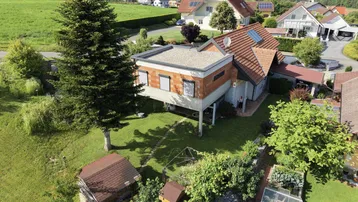 Luftaufnahme eines Hauses mit Flachdach und Ziegeldach in ländlicher Umgebung.