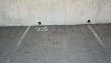 Parkplatz Nummer 43 mit Betonwand und Markierungen auf dem Asphalt.