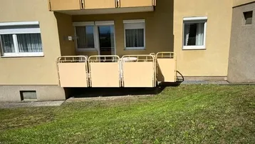 Balkon mit Sichtschutz und Blick auf eine grüne Rasenfläche.