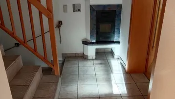 Heller Flur mit Fliesenboden, Holztreppe und einem integrierten Kamin für gemütliche Abende.