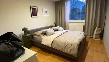 Gemütliches Schlafzimmer mit Holzboden, großem Bett und Blick ins Grüne.
