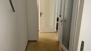 Heller Flur mit Vinylboden und mehreren Türen, der zu verschiedenen Räumen führt.
