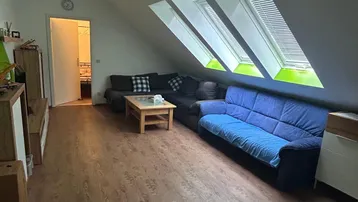 Gemütliches Wohnzimmer im Dachgeschoss mit Schrägen, Laminatboden und drei Dachfenstern.