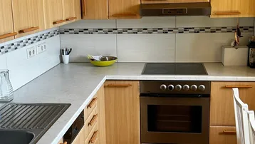 Helle Küche mit Holzfronten, Dachschräge und integrierten Geräten, ideal für gemütliches Kochen.