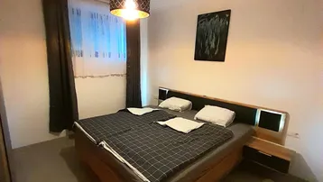 Gemütliches Schlafzimmer mit Doppelbett, Nachttischen und moderner Hängelampe.
