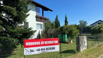 Außenansicht des Hauses mit Gartenbereich, Trampolin und einem "Wohnung zu vermieten"-Schild.