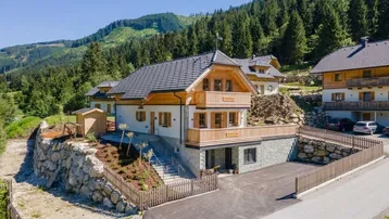 Modernes Holzhaus in alpiner Umgebung mit Bergblick und gepflegter Auffahrt.