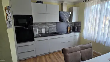 Moderne Küche mit integrierten Geräten, Arbeitsplatte und Fenster für natürliches Licht.