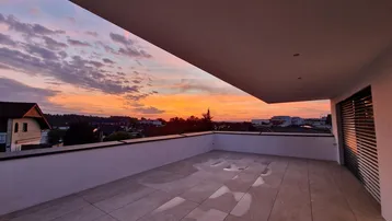 Große, geflieste Terrasse mit weitem Blick über die Stadt bei Sonnenuntergang.