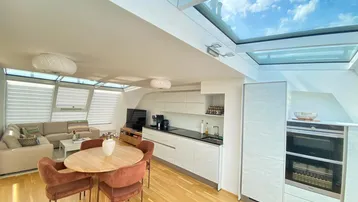Helles, offenes Wohn-Esszimmer mit integrierter Küche, Dachfenstern und Holzboden.