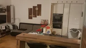 Offener Wohnbereich mit Holzboden, integrierter Küchenbar und Blick auf die moderne Küche.
