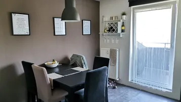 Gemütlicher Essbereich mit dunklem Tisch, bequemen Stühlen und Zugang zum Balkon, ideal für Mahlzeiten.