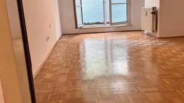 Helles Zimmer mit Parkettboden und Fenster zum Innenhof, bereit zur individuellen Gestaltung.