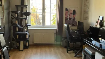 Geräumiger Wohnbereich mit Holzfußboden, Fenster und vielseitiger Nutzung als Arbeits- und Freizeitraum.