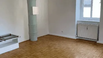 Helles Zimmer mit Parkettboden und großem Fenster, bereit zur individuellen Gestaltung.