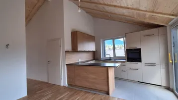 Moderne Küche mit hellen Holzfronten, Kochinsel und Zugang zu einem Balkon oder einer Terrasse.