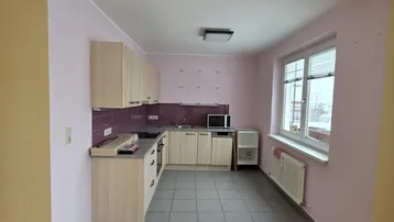 Helle Küche mit hellen Holzschränken, grauen Fliesen und einem Fenster, bereit zur individuellen Gestaltung.