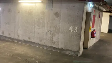 Tiefgarage mit Betonwänden, Leuchtstoffröhren und Feuerlöscher, Stellplatz 43.