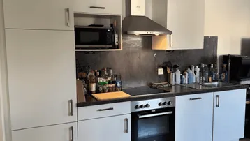 Funktionale Küche mit weißen Schränken, integriertem Backofen und Mikrowelle.