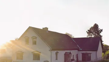Traditionelles Haus im Sonnenuntergang mit Satteldach und gepflegtem Vorgarten.