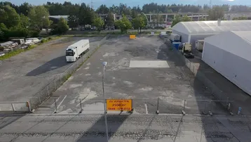 Luftaufnahme eines großen, eingezäunten Industriegrundstücks mit einem Lastwagen und einem 'Zu vermieten'-Schild.