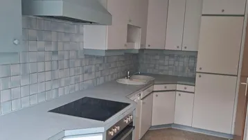 Küche mit hellblauen und weißen Schränken, integriertem Kochfeld und Backofen.