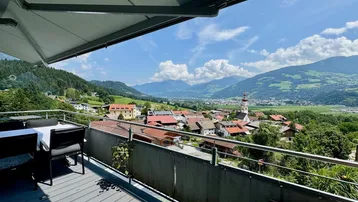 Balkon mit Esstisch und Markise, bietet einen weiten Blick über das Tal und die umliegenden Berge.