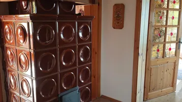 Traditioneller Kachelofen im Eingangsbereich mit Fliesenboden und Holztüren.