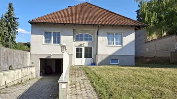 Einfamilienhaus mit gepflasterter Auffahrt, integrierter Garage und Satteldach.