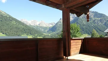 Geräumiger Balkon mit Holzelementen und atemberaubendem Blick auf die umliegende Berglandschaft.