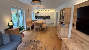 Offener Wohn- und Essbereich mit moderner Küche, Holzboden und Zugang zur Terrasse.